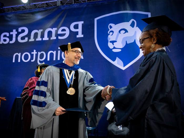 Interim Chancellor 安德鲁8月 presents a 宾州州立大学阿宾顿分校 student with her diploma